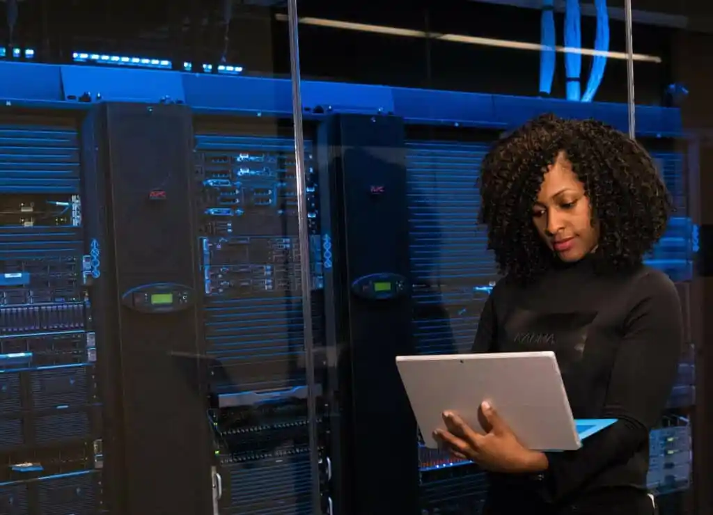 Woman with dark curly hair works in a controlled server room